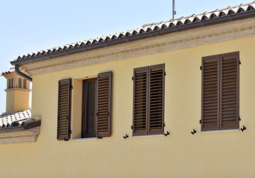 Edificio giallo con persiane marroni e tetto di tegole.