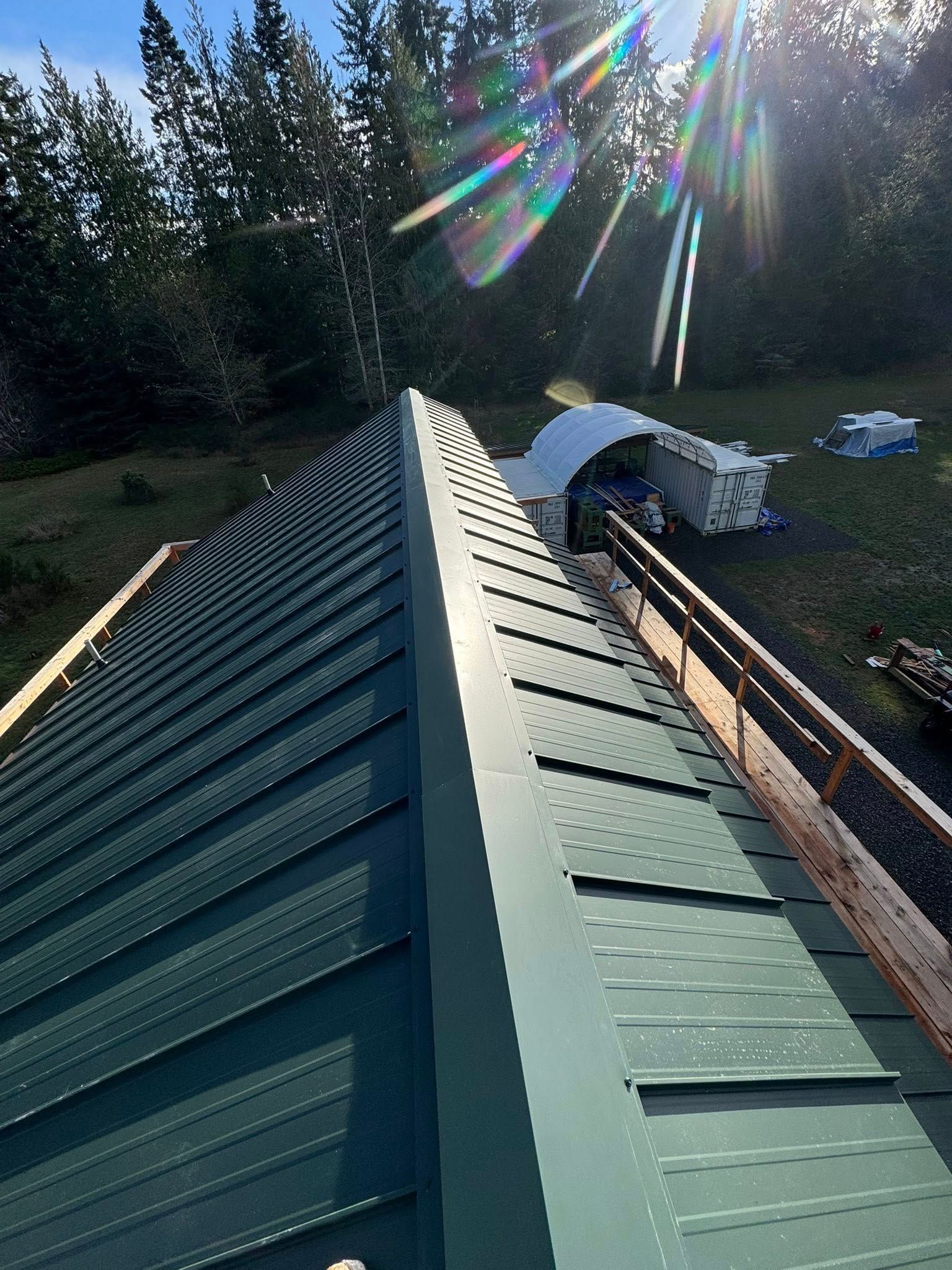 Green metal roof with a ridge cap, sun shining.