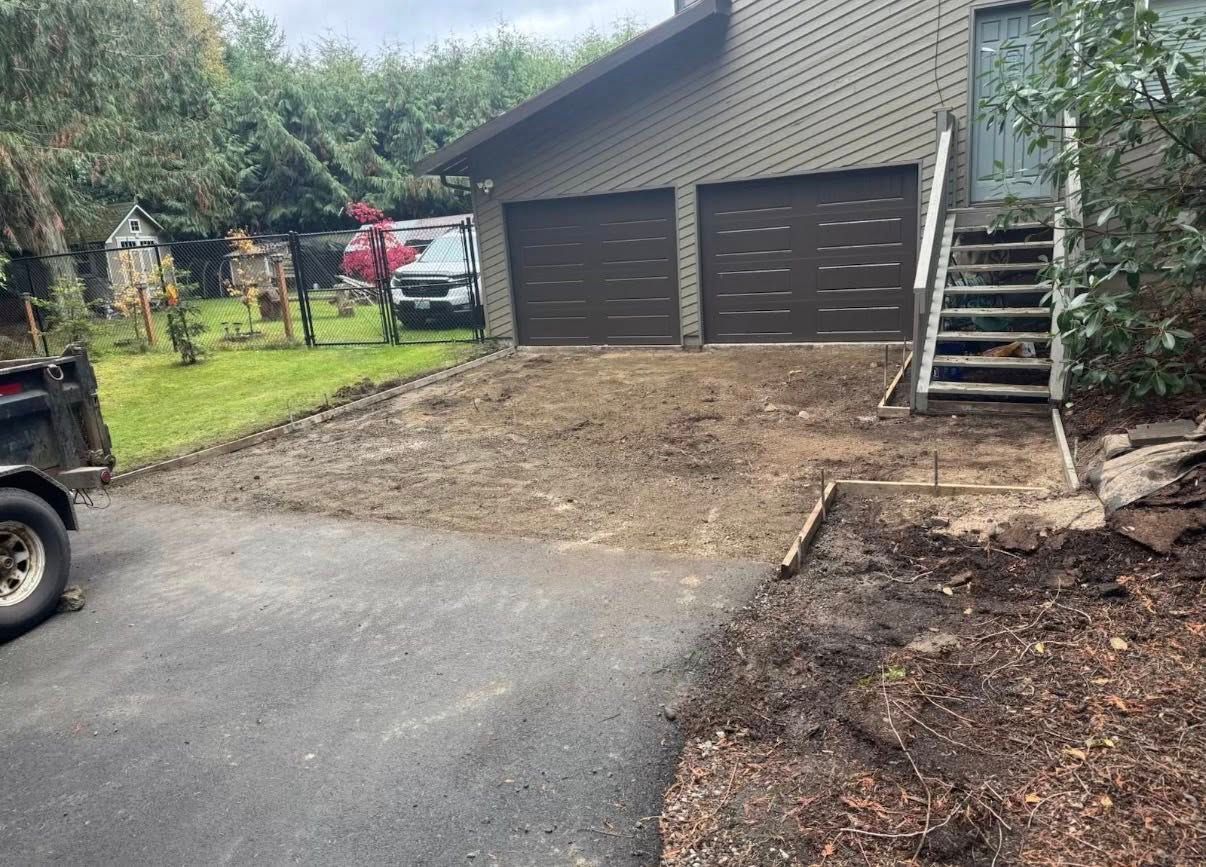 Driveway with two-car garage, dirt patch, and staircase. A small truck and landscaping work are visible.