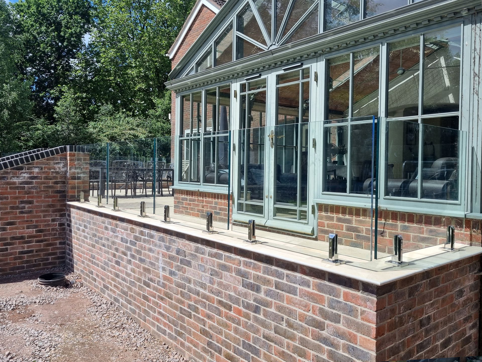 Brick wall with glass railing and windows, leading to a sunroom.