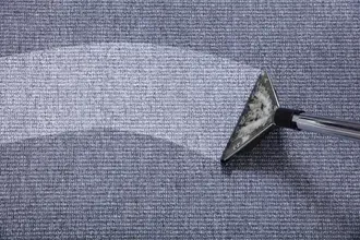 Vacuum nozzle cleaning a gray upholstered fabric surface