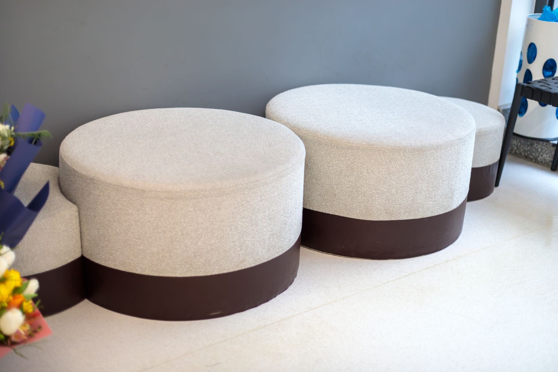 Two round gray ottomans with dark brown bases in a bright room