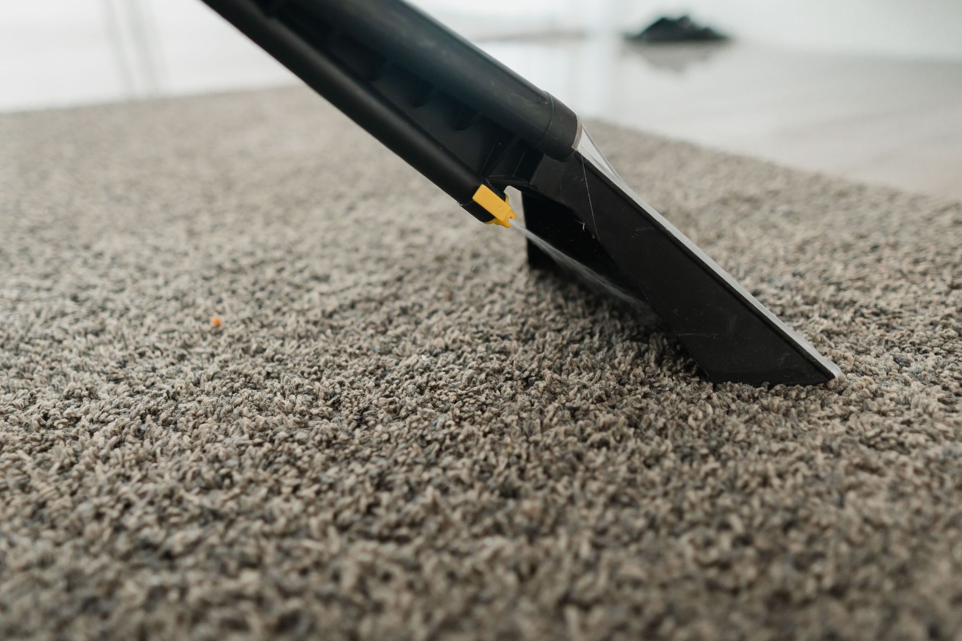 Carpet cleaning nozzle extracting dirt from beige carpet close-up