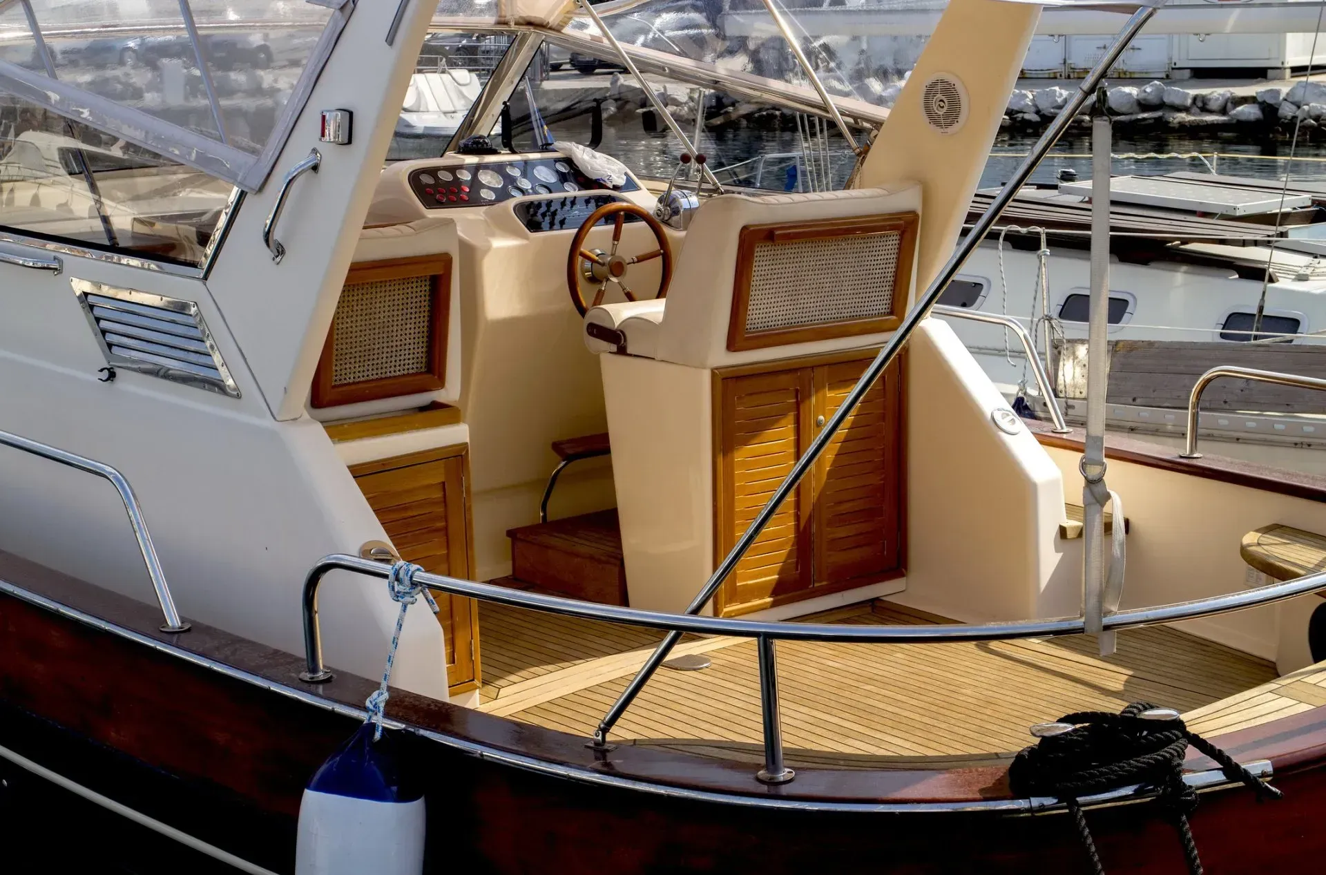 Small sailboat cockpit with tan cushions and wooden trim docked at a marina.