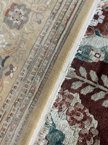 Close-up of two patterned rugs meeting at a beige fringe seam.
