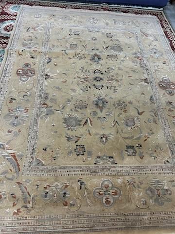 Beige floral rug with faded border and ornate central medallion pattern on a floor