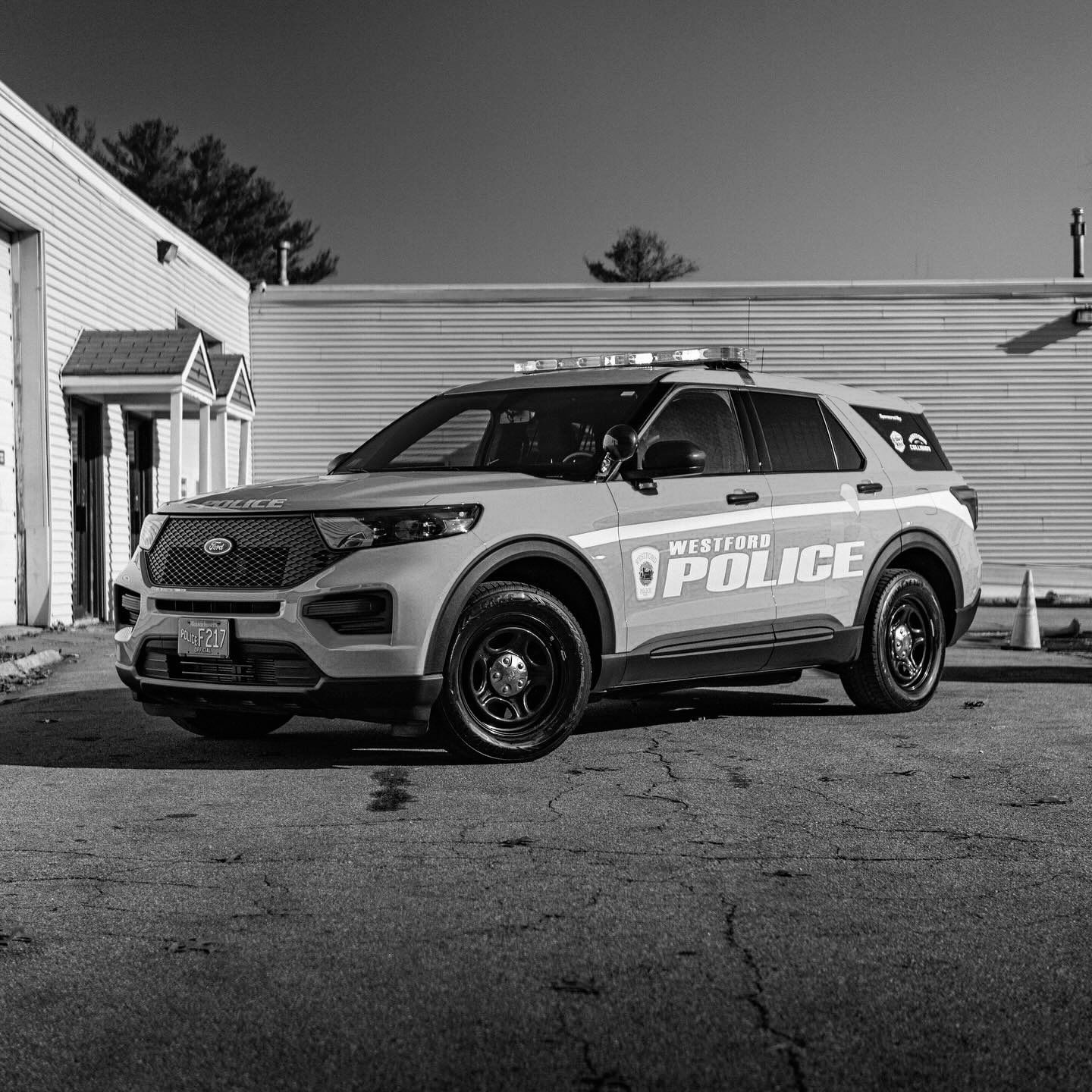 A police car is parked in front of a building in a black and white photo.