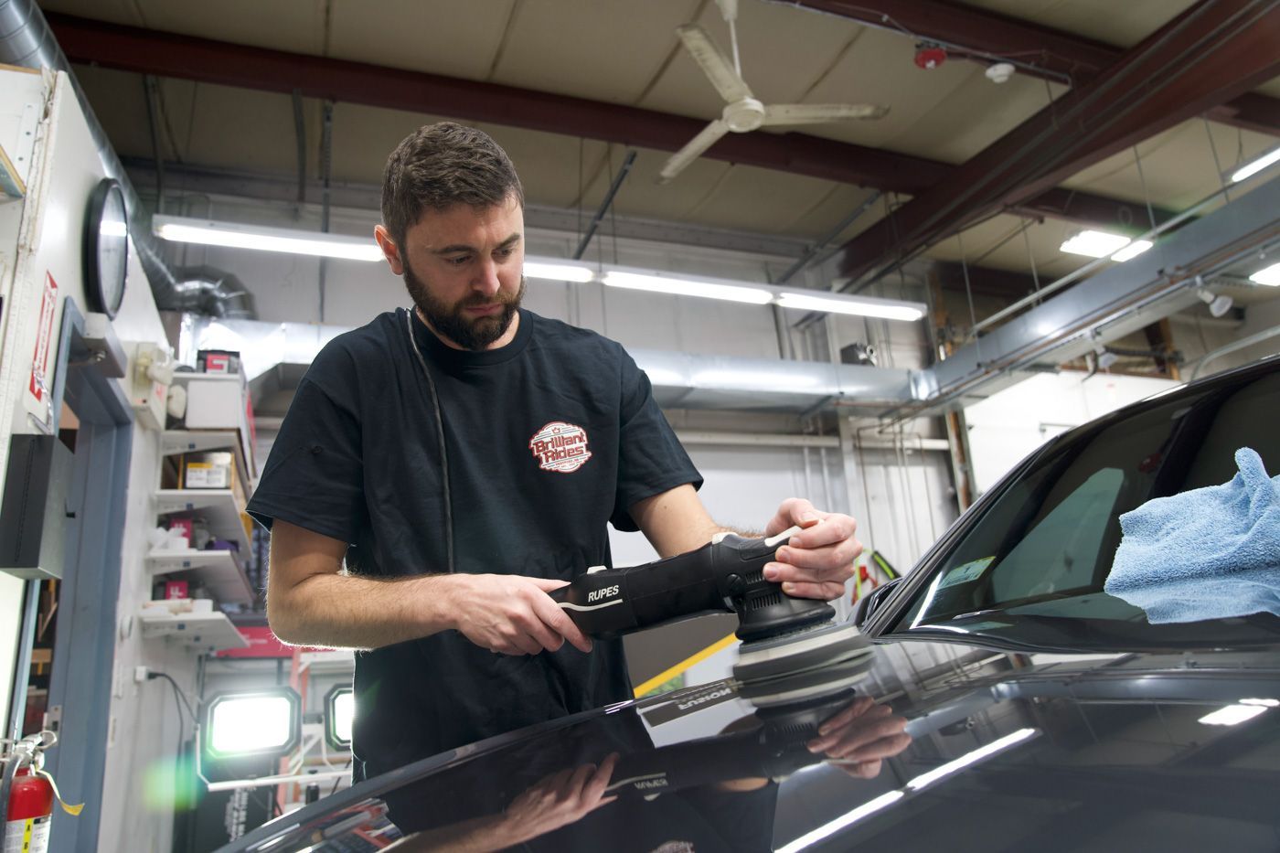 A man is polishing a car in a garage.
