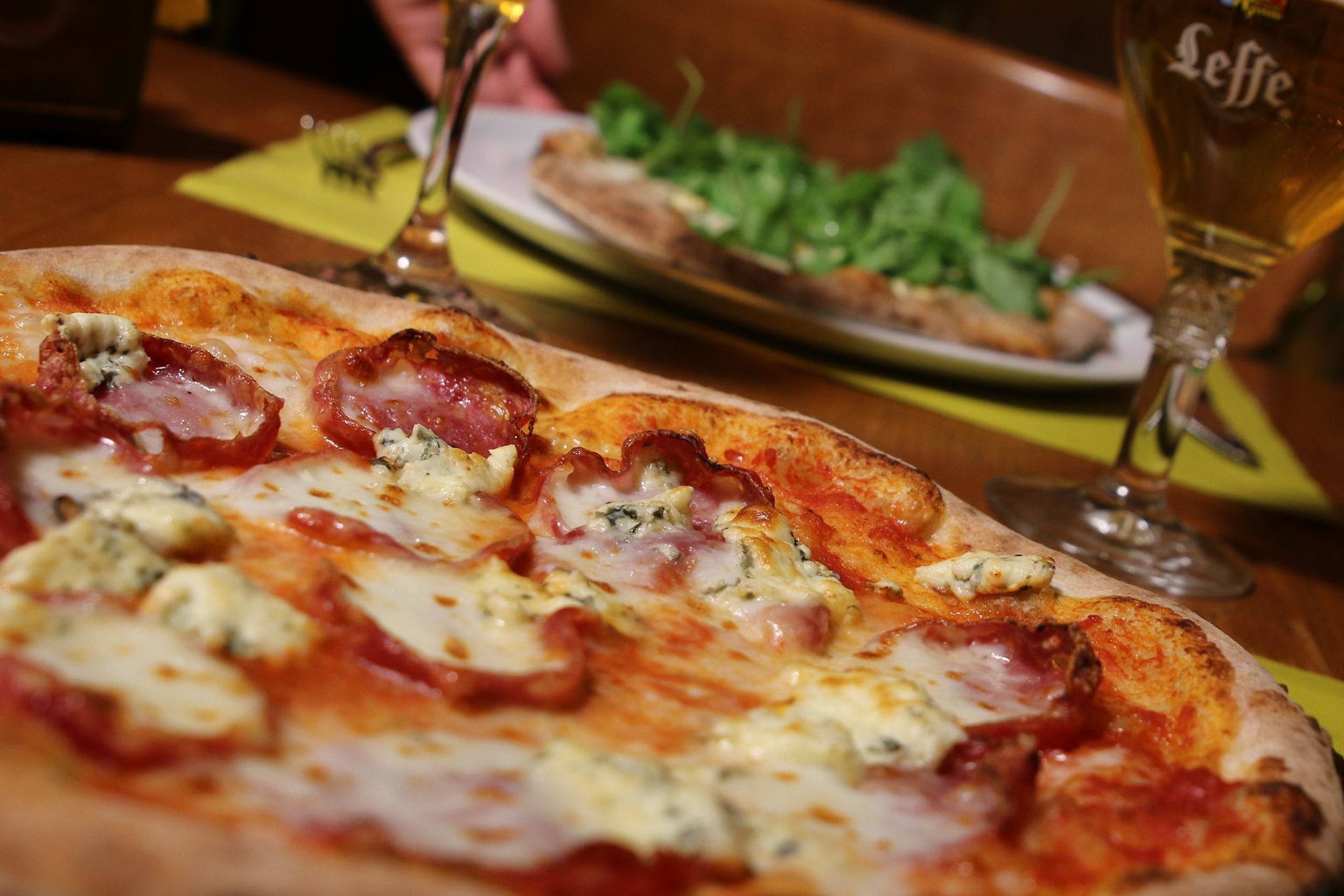 Pizza con pepperoni e gorgonzola, con una birra e un altro piatto in un ristorante.