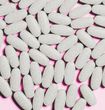 Gray oval pills scattered on a pink surface.