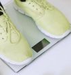 Pair of lime green sneakers on a white digital scale.