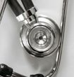 Close-up of a silver stethoscope's head and tubing against a white background.
