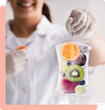 Person in lab coat holding IV bag filled with fruit, smiling.