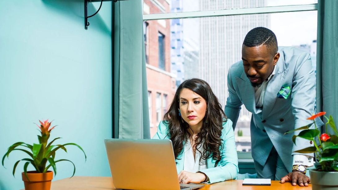 A man and a woman are looking at a laptop computer.