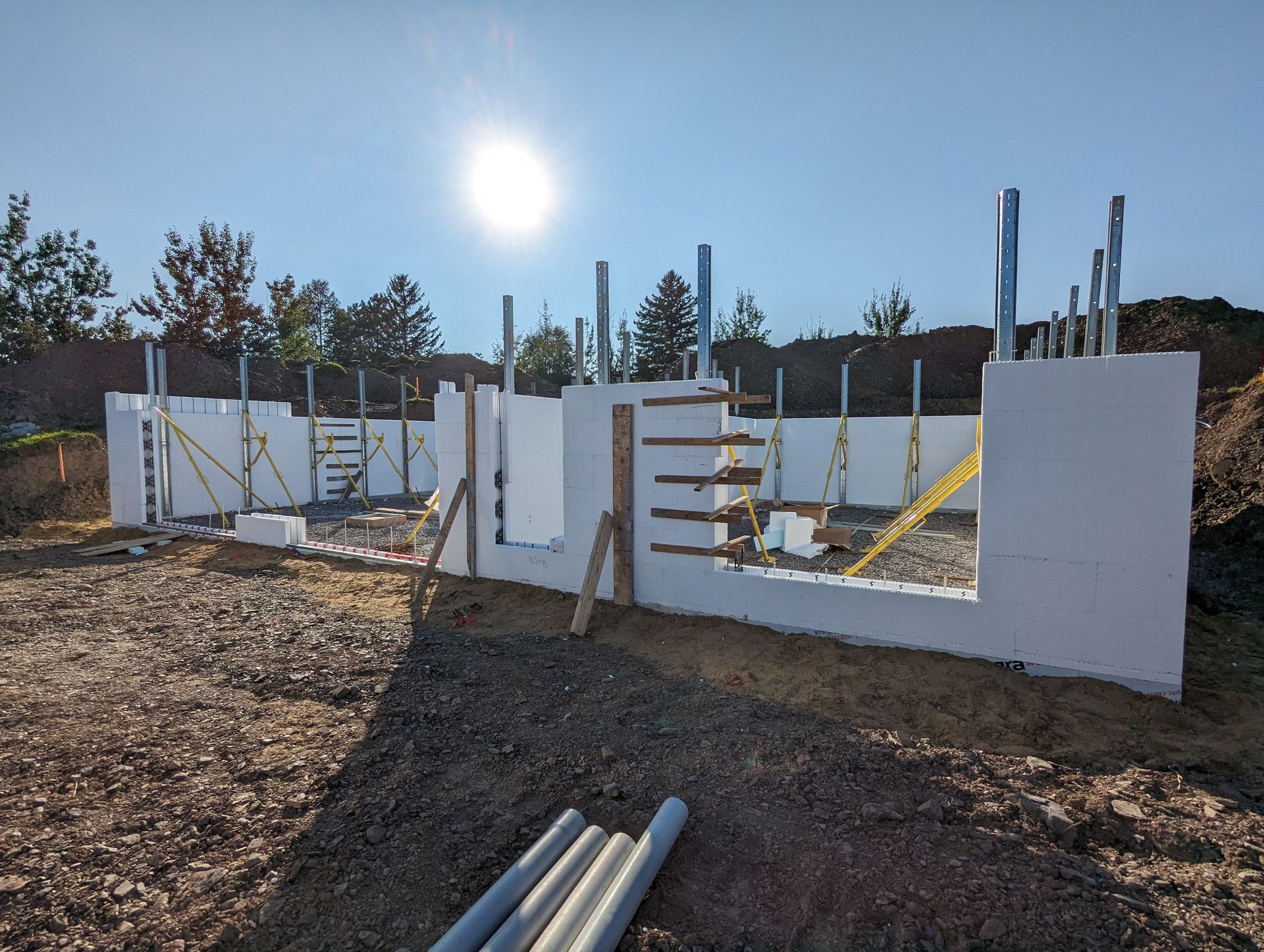 Un grand mur blanc est en train d'être construit dans un champ de terre.