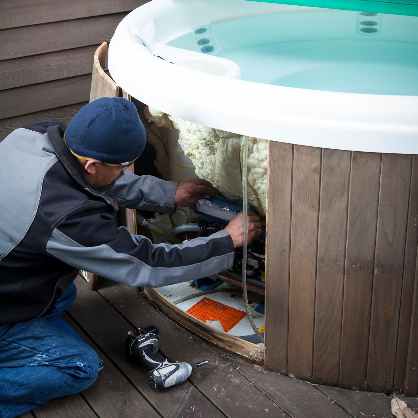 A man is working on a hot tub on a deck