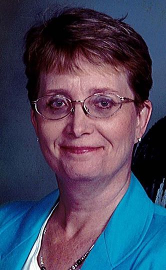 A woman in a green sweater is smiling for the camera