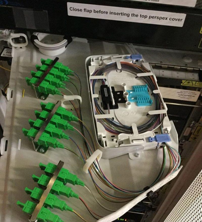 A box with green connectors and a sign that says close flap before inserting the top perspex cover