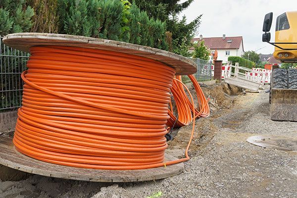 A large spool of orange fiber optic cable is sitting on top of a wooden spool.