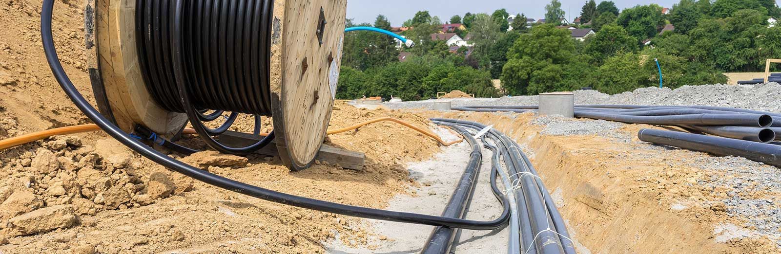 A spool of wires is sitting in the dirt on a construction site.
