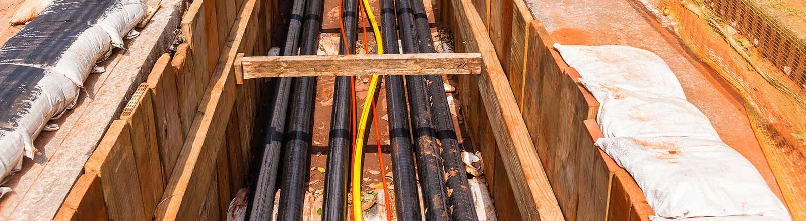 A bunch of electrical wires are being installed in a trench.