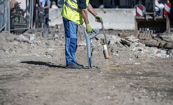 A construction worker is using a shovel to dig a hole in the ground.