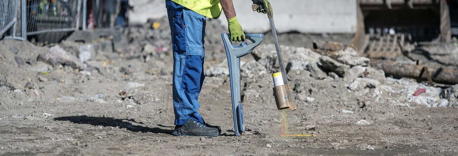 A construction worker is using a drill to dig a hole in the ground.
