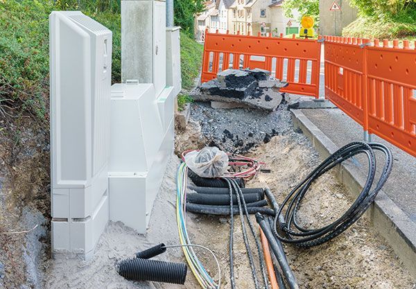 A bunch of wires are laying in the dirt next to a fence.
