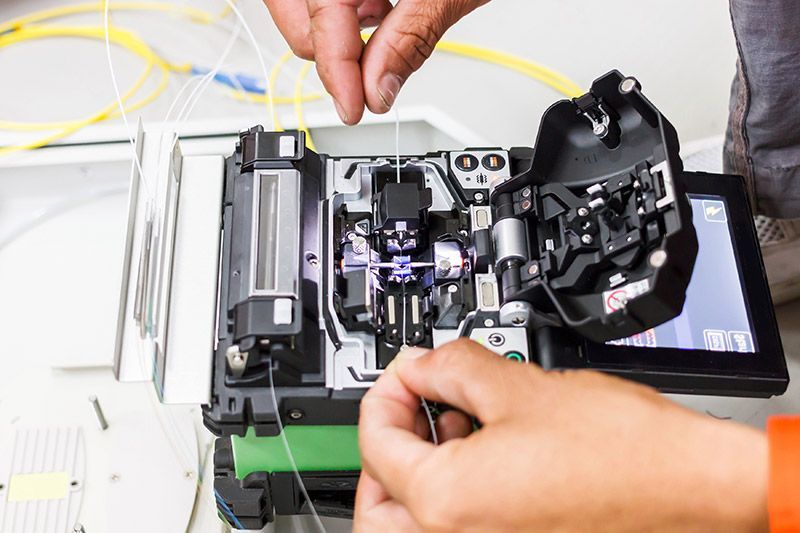 A person is working on a machine that is cutting fiber optic cables.