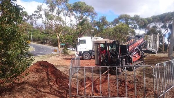 A tractor is digging a hole in the ground next to a truck.