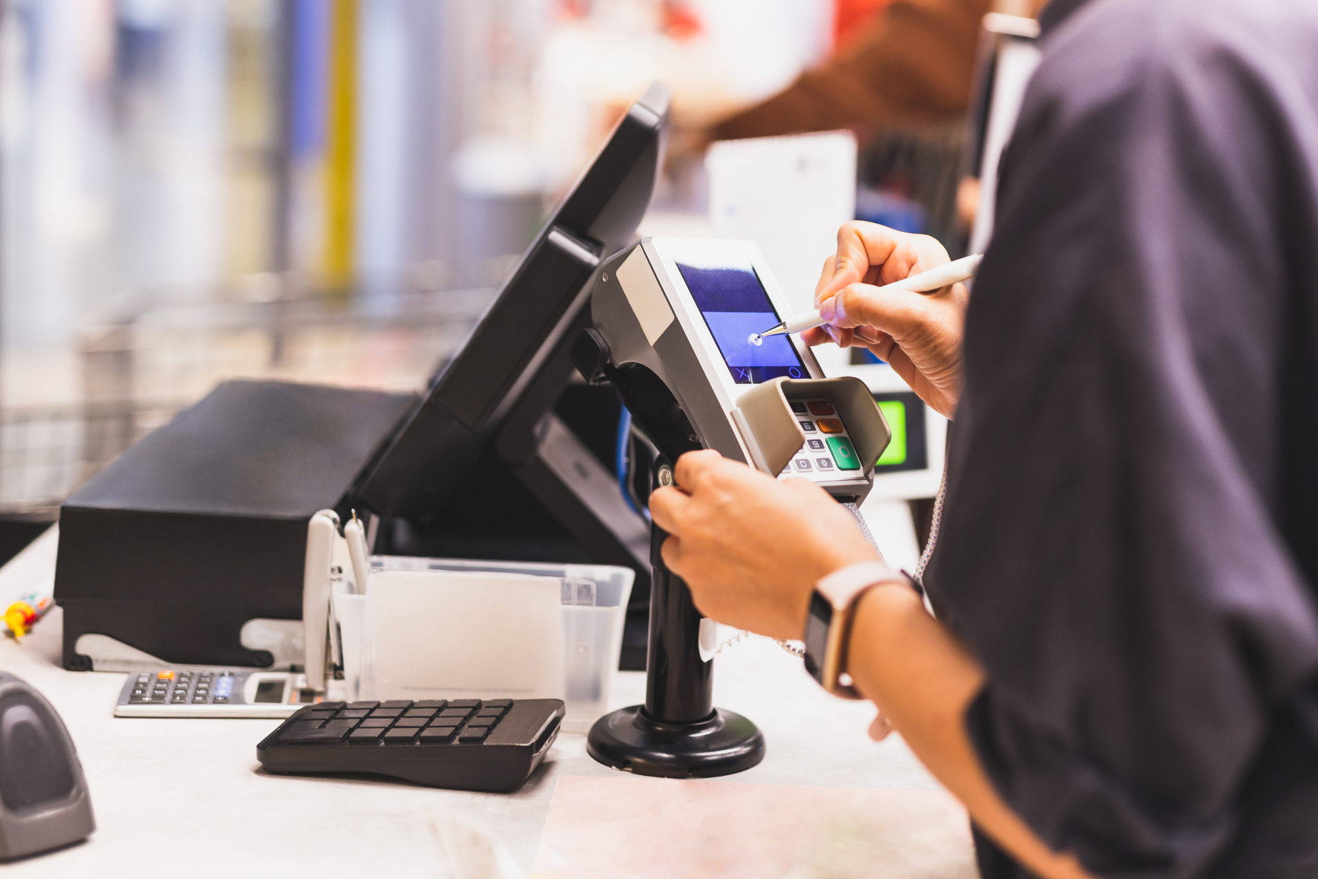 Person paying with phone at a store checkout counter.