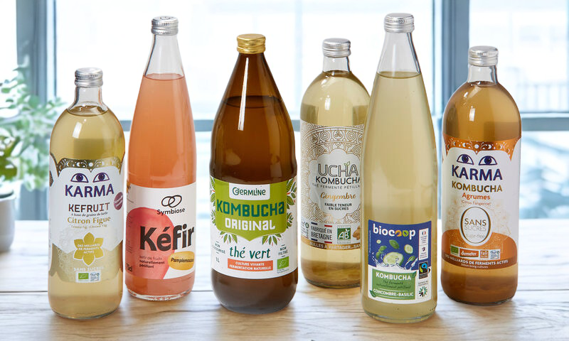 Un groupe de bouteilles de kombucha sont posées sur une table en bois.