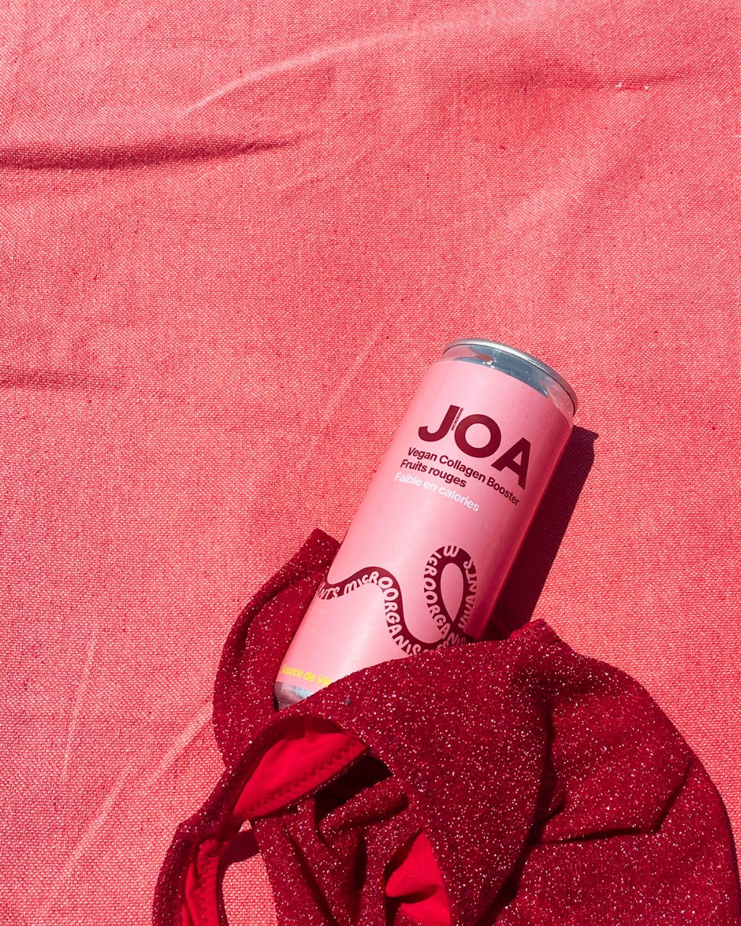 Une canette rose de Joa est posée sur une serviette rose.