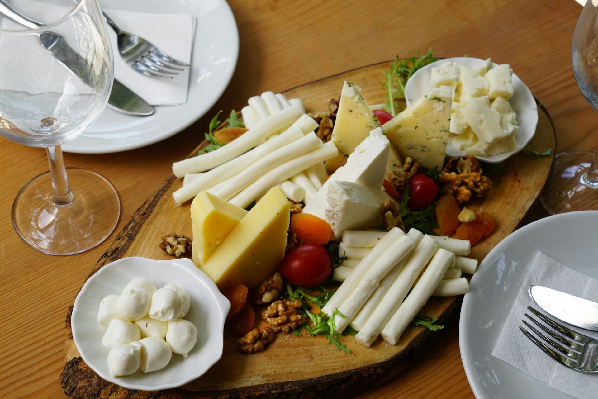 Une planche à découper en bois avec une variété de fromages et de noix dessus.