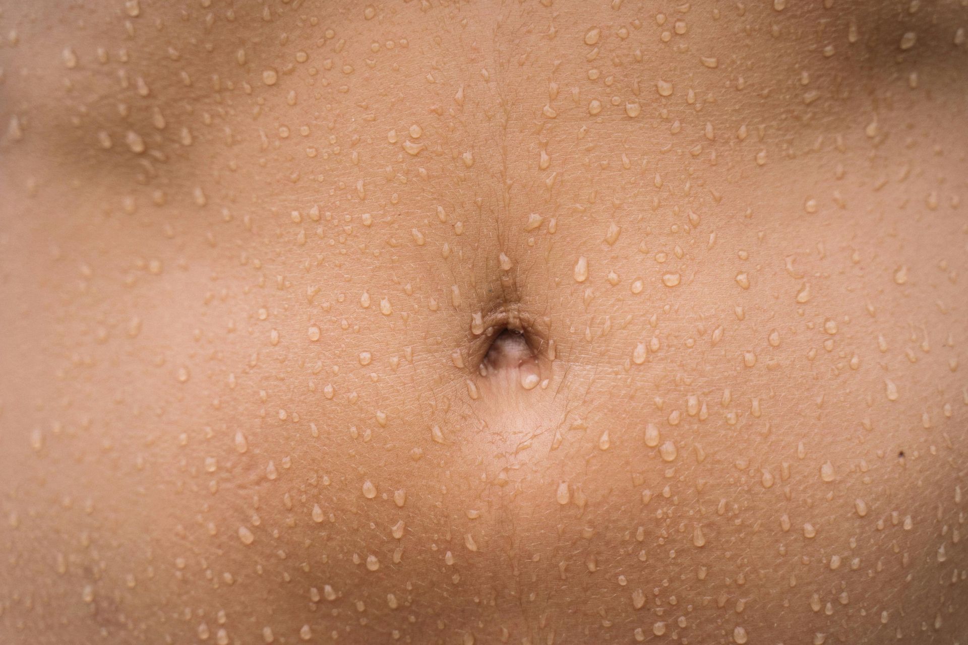 Un gros plan du ventre d'une personne avec des gouttes d'eau dessus.