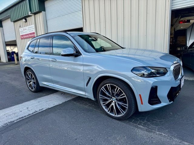 Light blue BMW SUV parked outside a warehouse garage