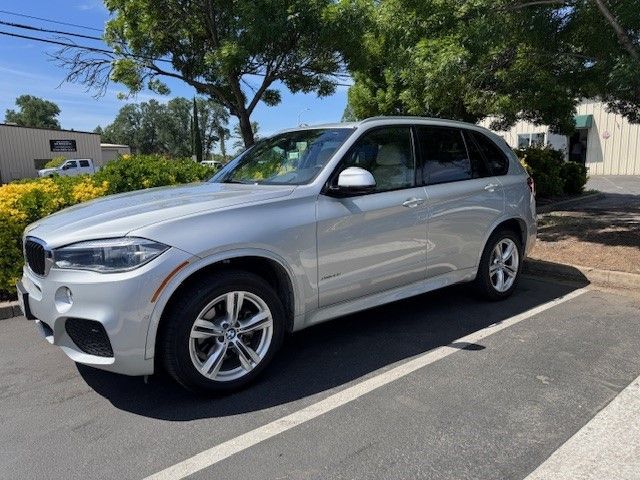 A silver bmw x5 is parked in a parking lot.