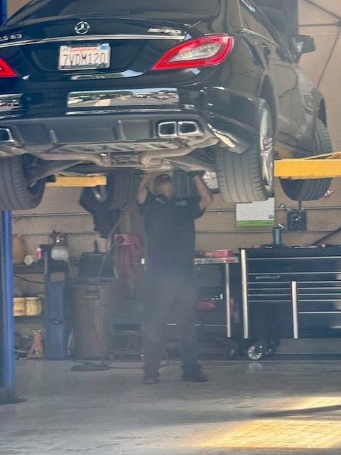 A man is working under a car in a garage.