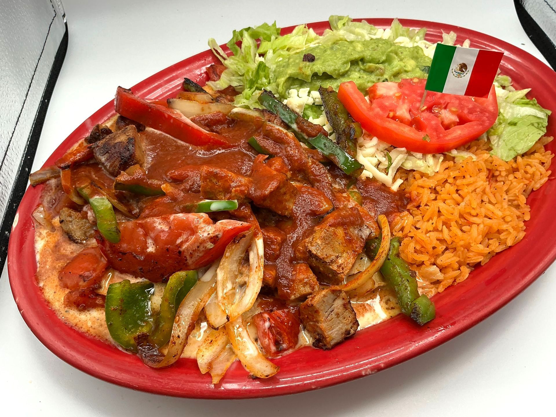 Grilled open-faced sandwich topped with melted cheese, vegetables, and meat on a black plate