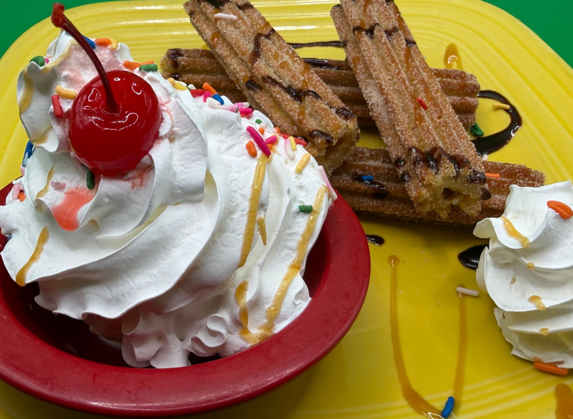 Whipped cream sundae with cherry and wafer sticks on a bright yellow plate
