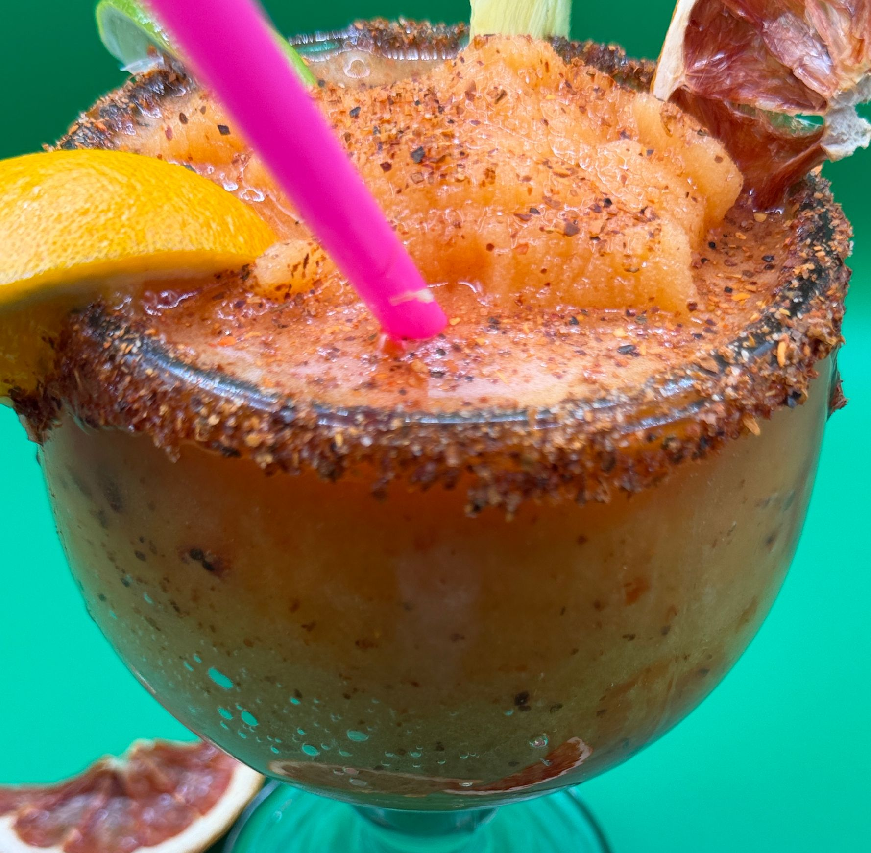 Spicy cocktail in a sugar-rimmed glass with pineapple garnish and a pink straw