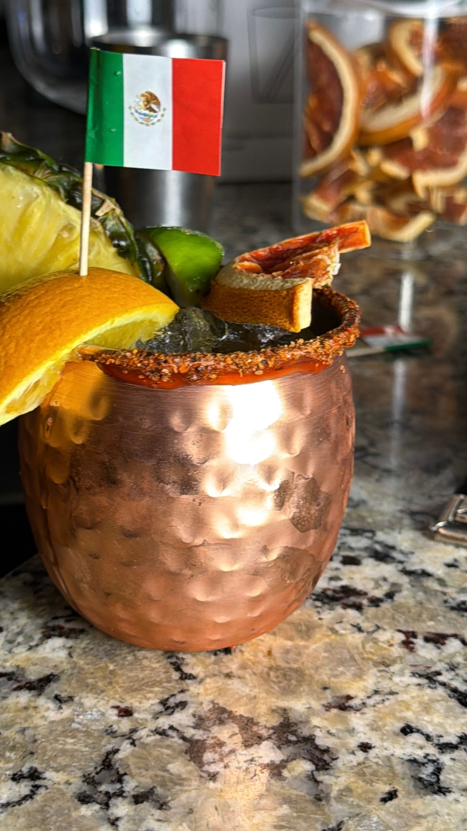 Copper mug with a Mexican flag garnish and a salted rim on a granite countertop