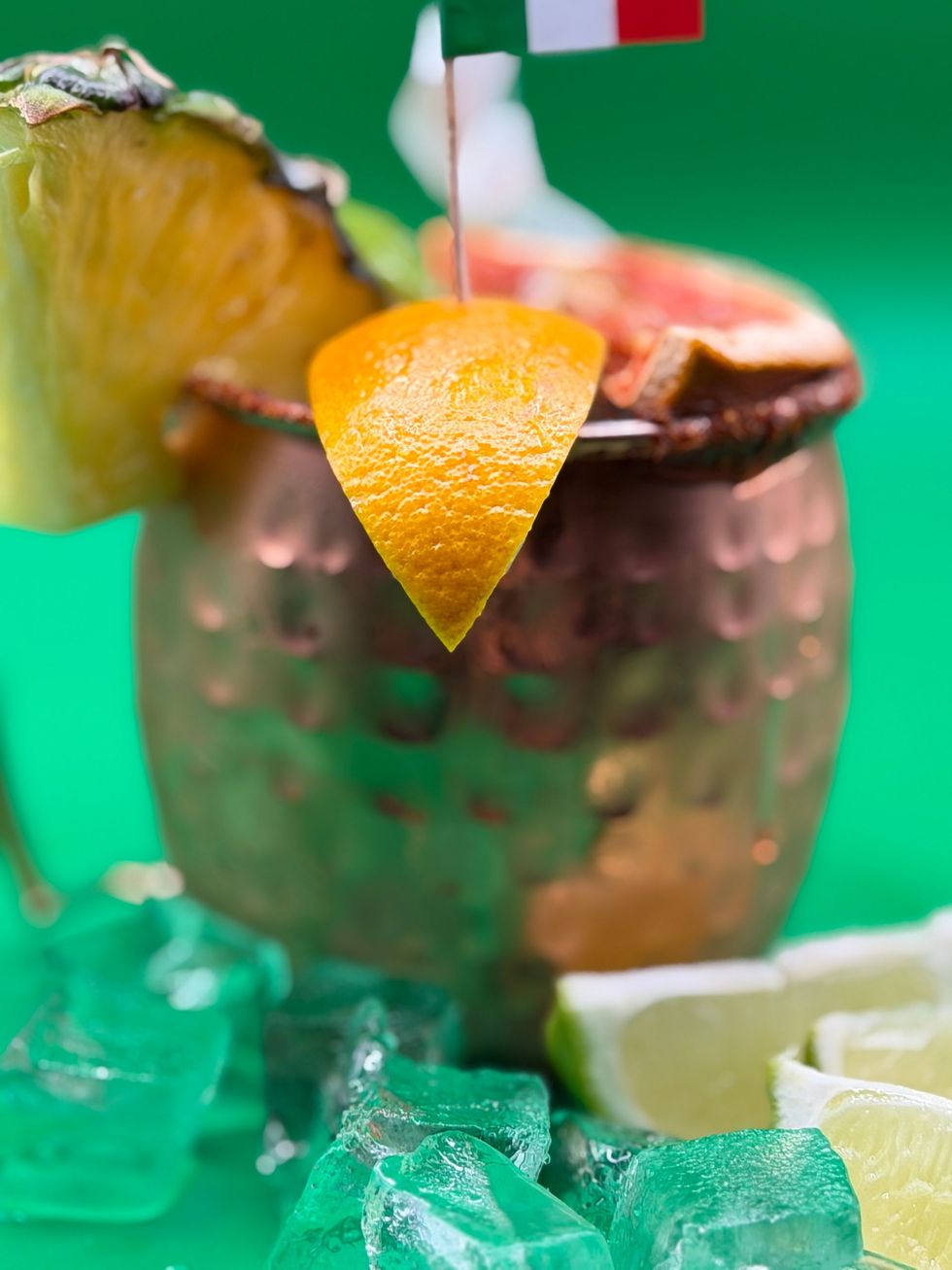 Close-up of a chocolate dessert with a lemon wedge and red straw on a green background