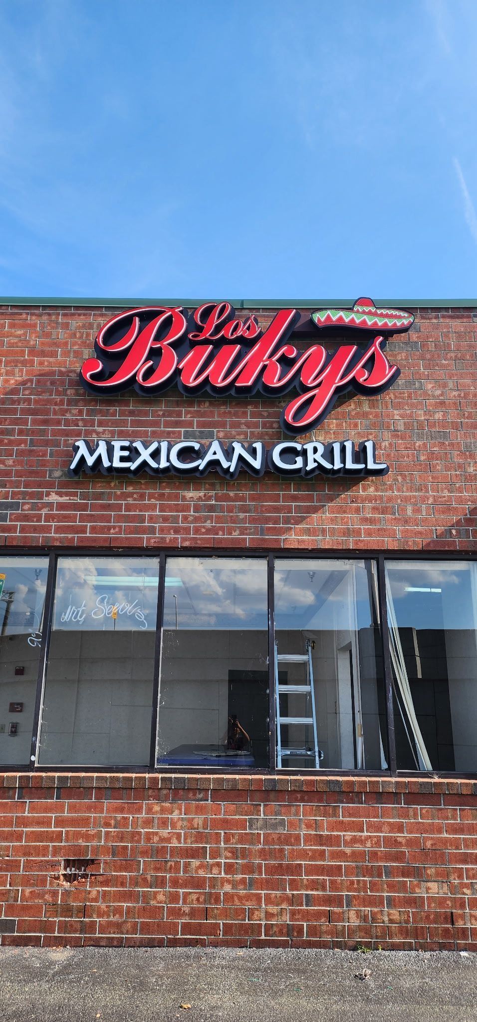 Brick storefront sign for Billy’s Mexican Grille under a blue sky