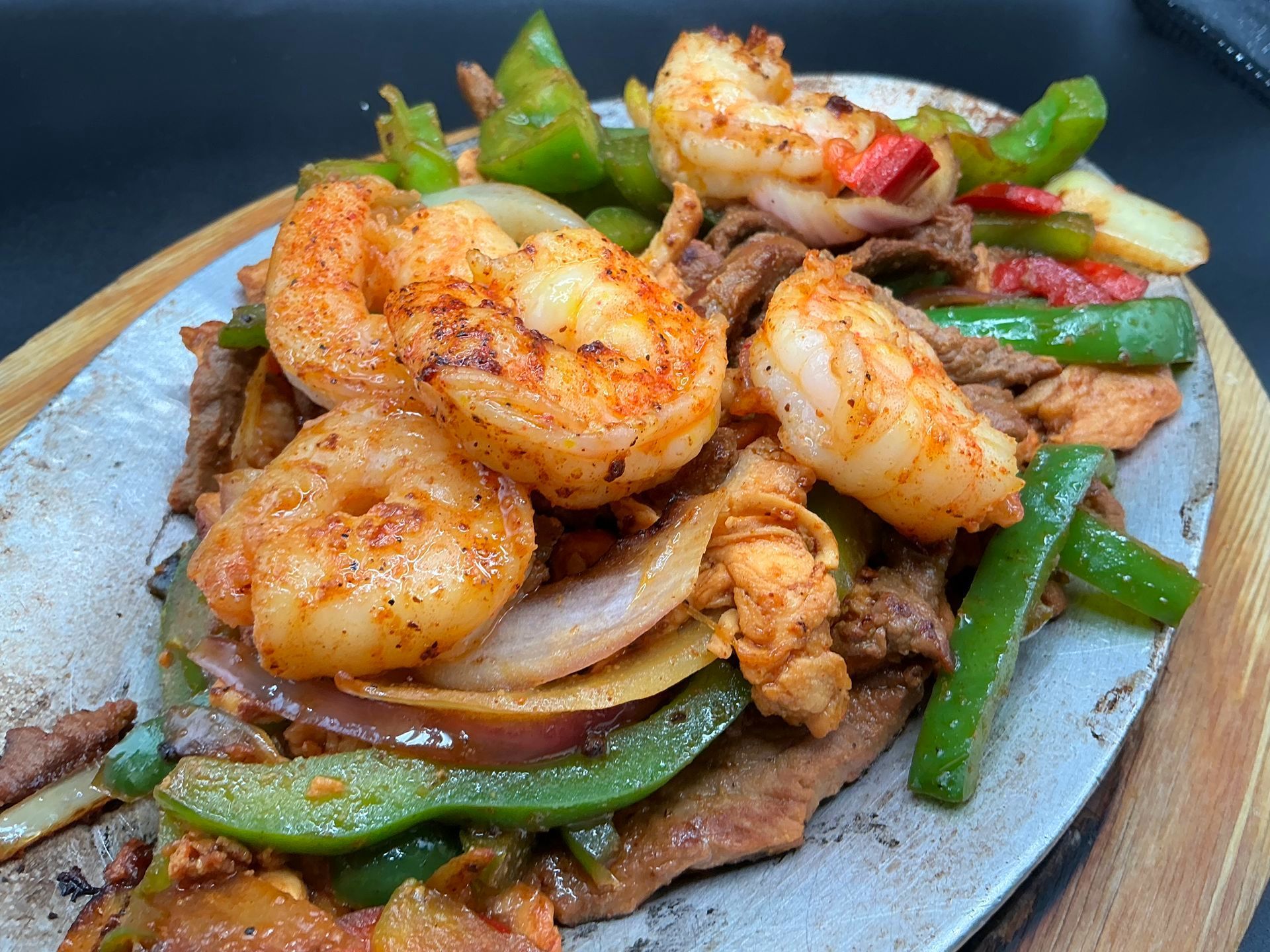 Shrimp and vegetables served on a sizzling platter with green beans, onions, and peppers