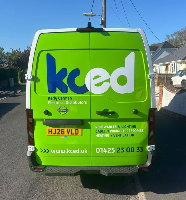 Bright green KCED electrical distribution van parked on a street, rear view with company logo and contact details.