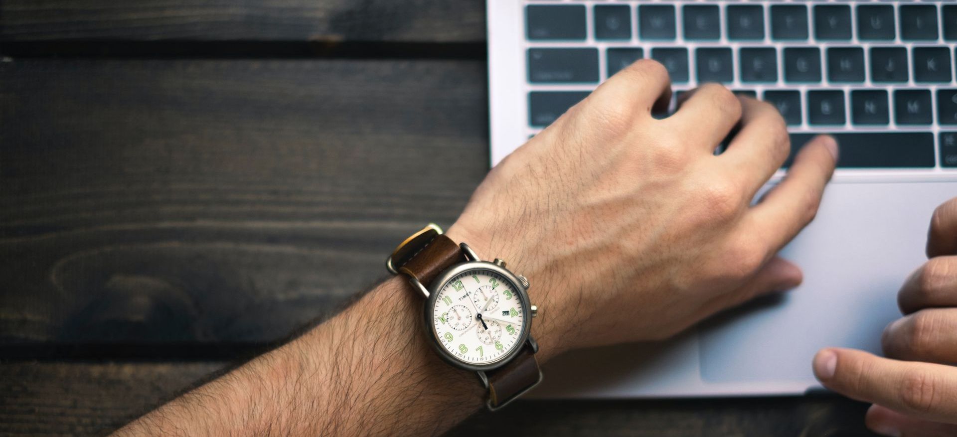 Hand wearing watch working on computer