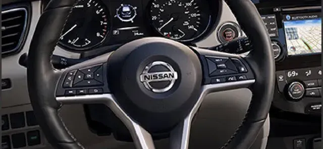 Interieur van een Nissan met stuurwiel, dashboardmeters en centraal infotainmentscherm.