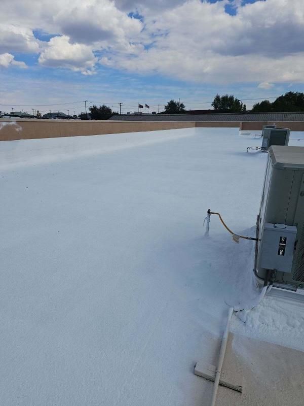Rooftop with a white-coated surface, HVAC units, and a cloudy sky overhead