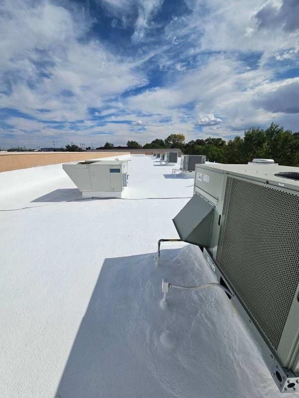 Flat white rooftop with HVAC units under a cloudy blue sky